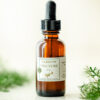 Amber tincture bottle among herbs with white background